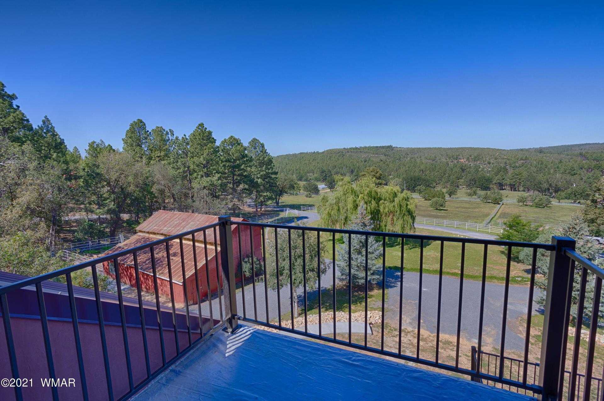 a deck with metal railings overlooking a red barn in Pinedale Arizona